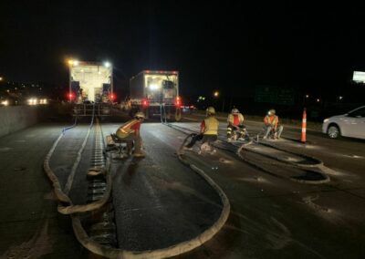 men injecting foam under road at night with truck lights glowing in the background