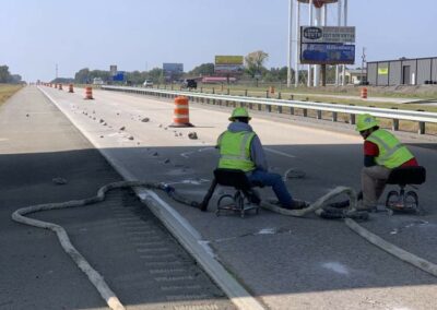 Workers performing deep foam injection along highway to raise surface